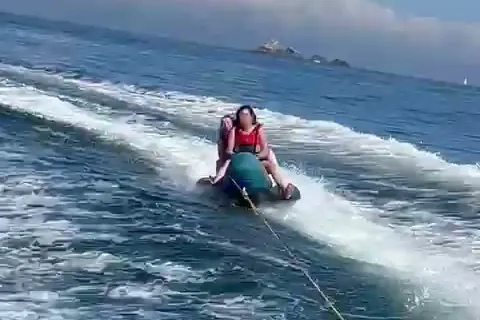 Deux passagers sur la bouée tractée, dans le sillage du bateau